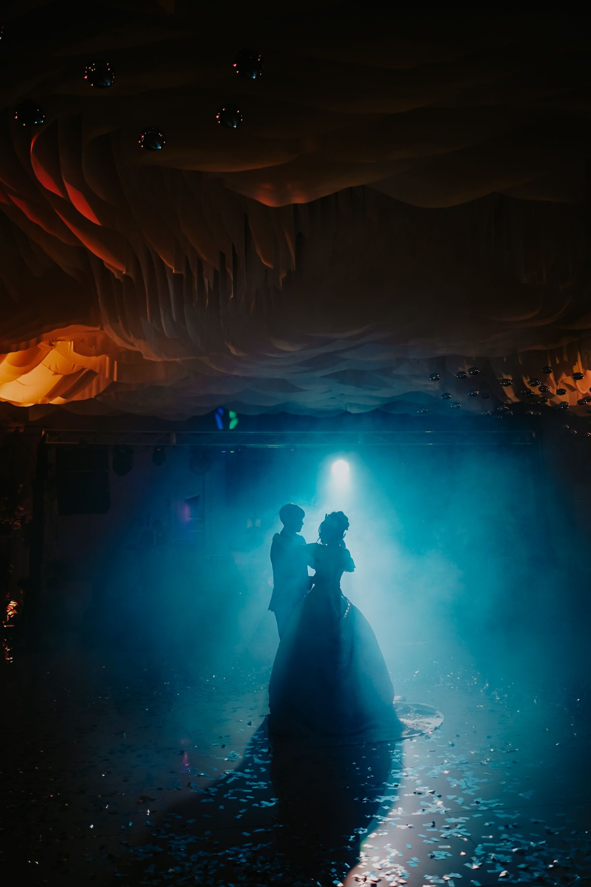 Two silhouetted figures stand in dramatic backlit blue cave lighting creating a mystical atmospheric scene.