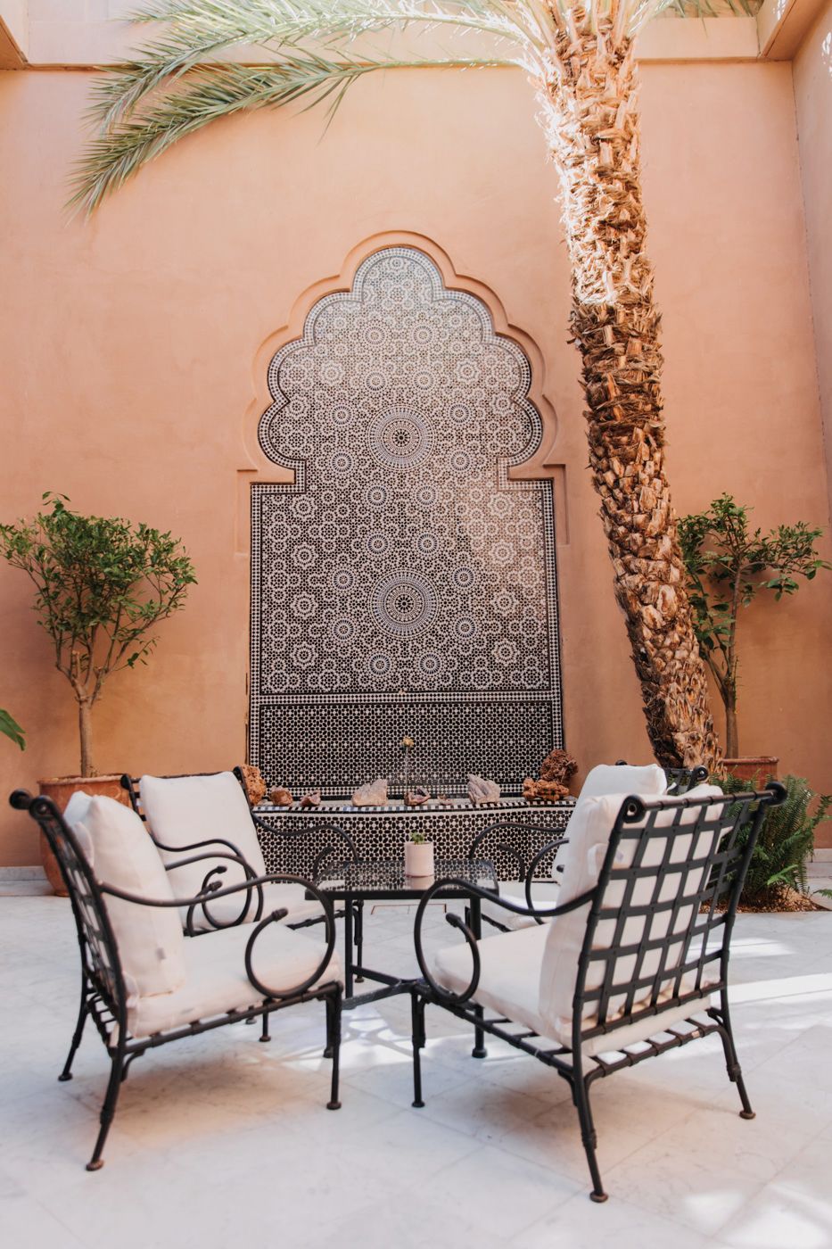 Intimate outdoor seating area with ornate Moroccan fountain and wrought iron furniture.