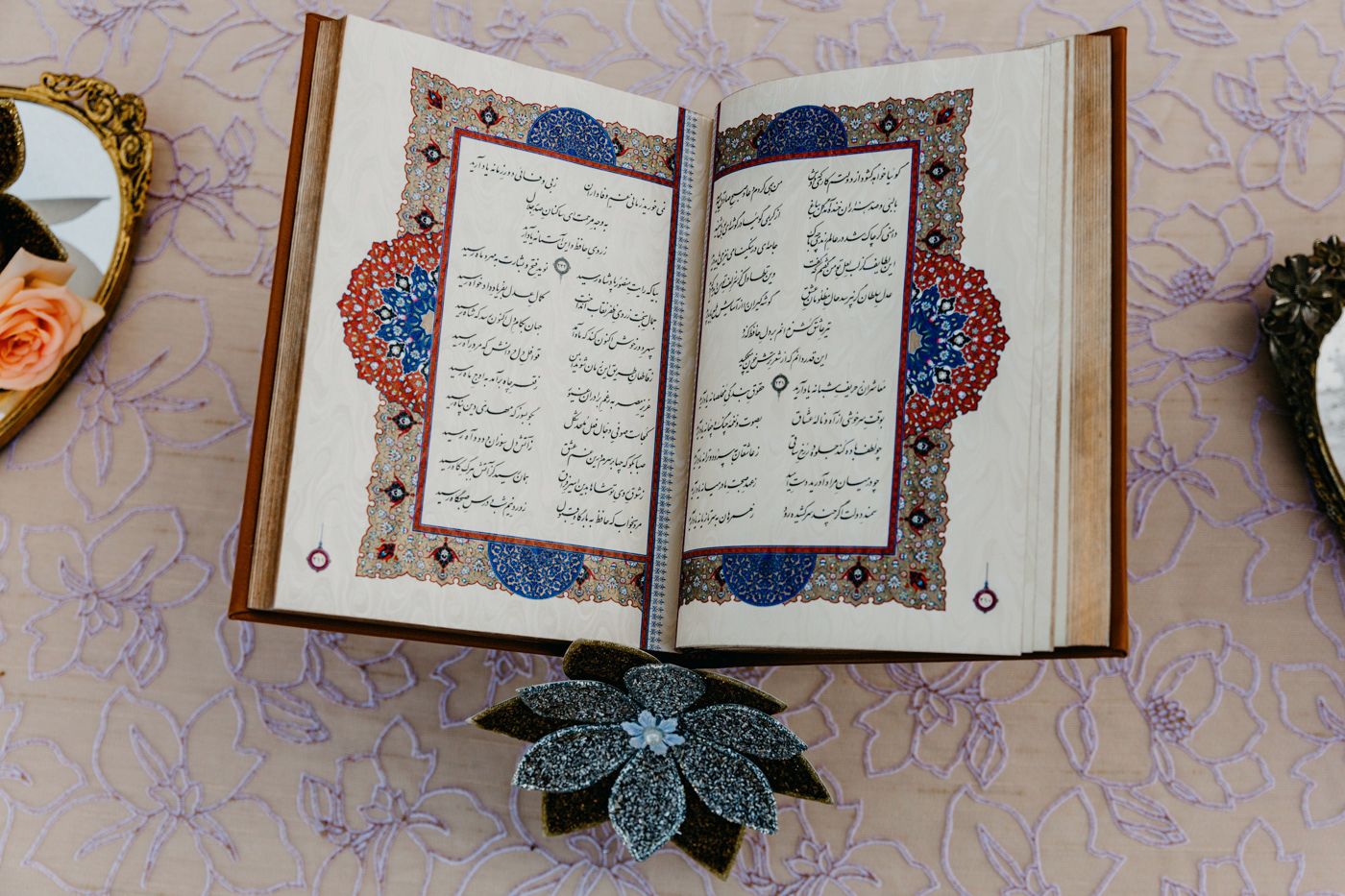 Open decorative book with intricate blue and gold Arabic calligraphy patterns.