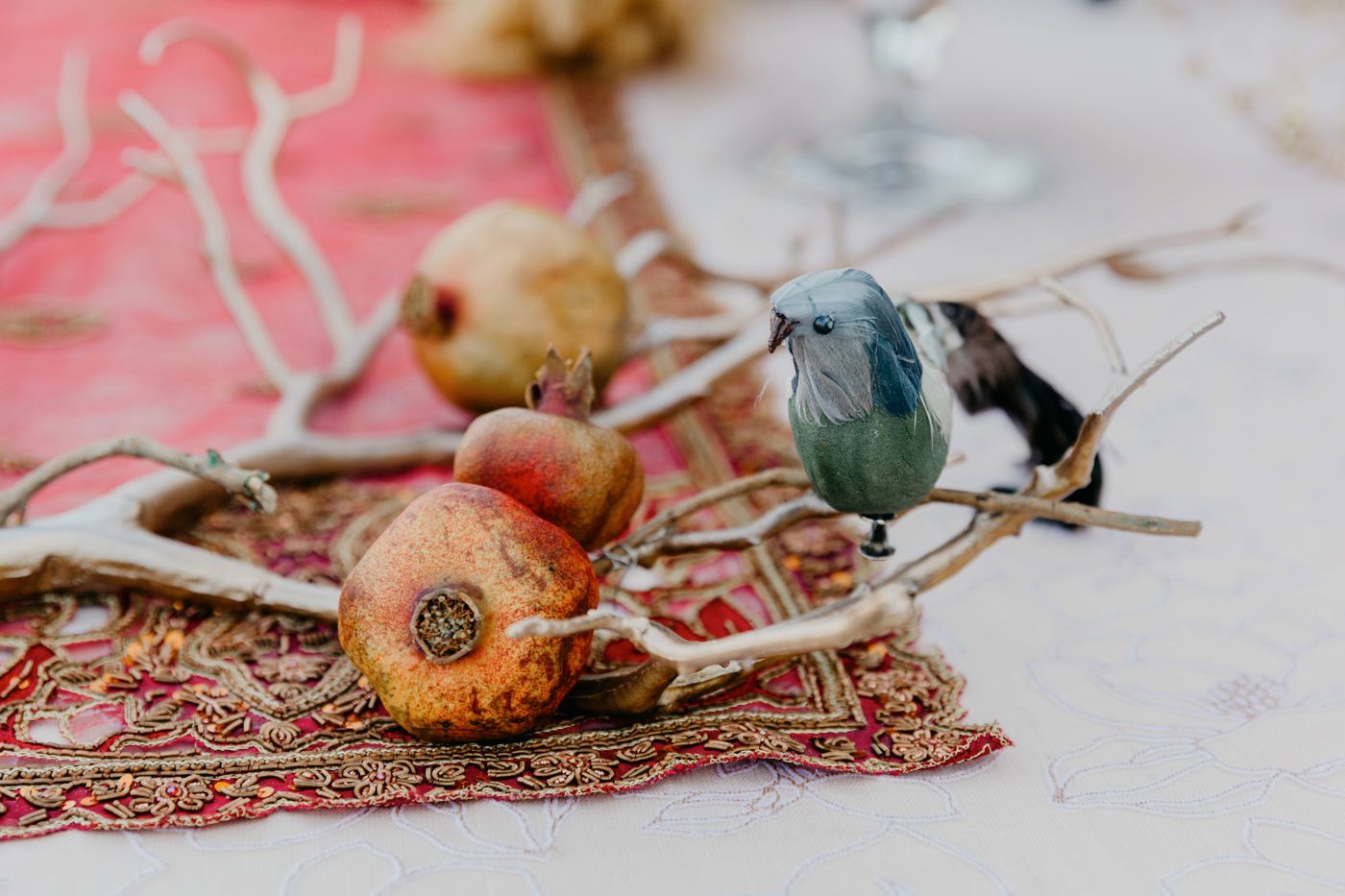 Small decorative birds and objects arranged on a vintage patterned textile.