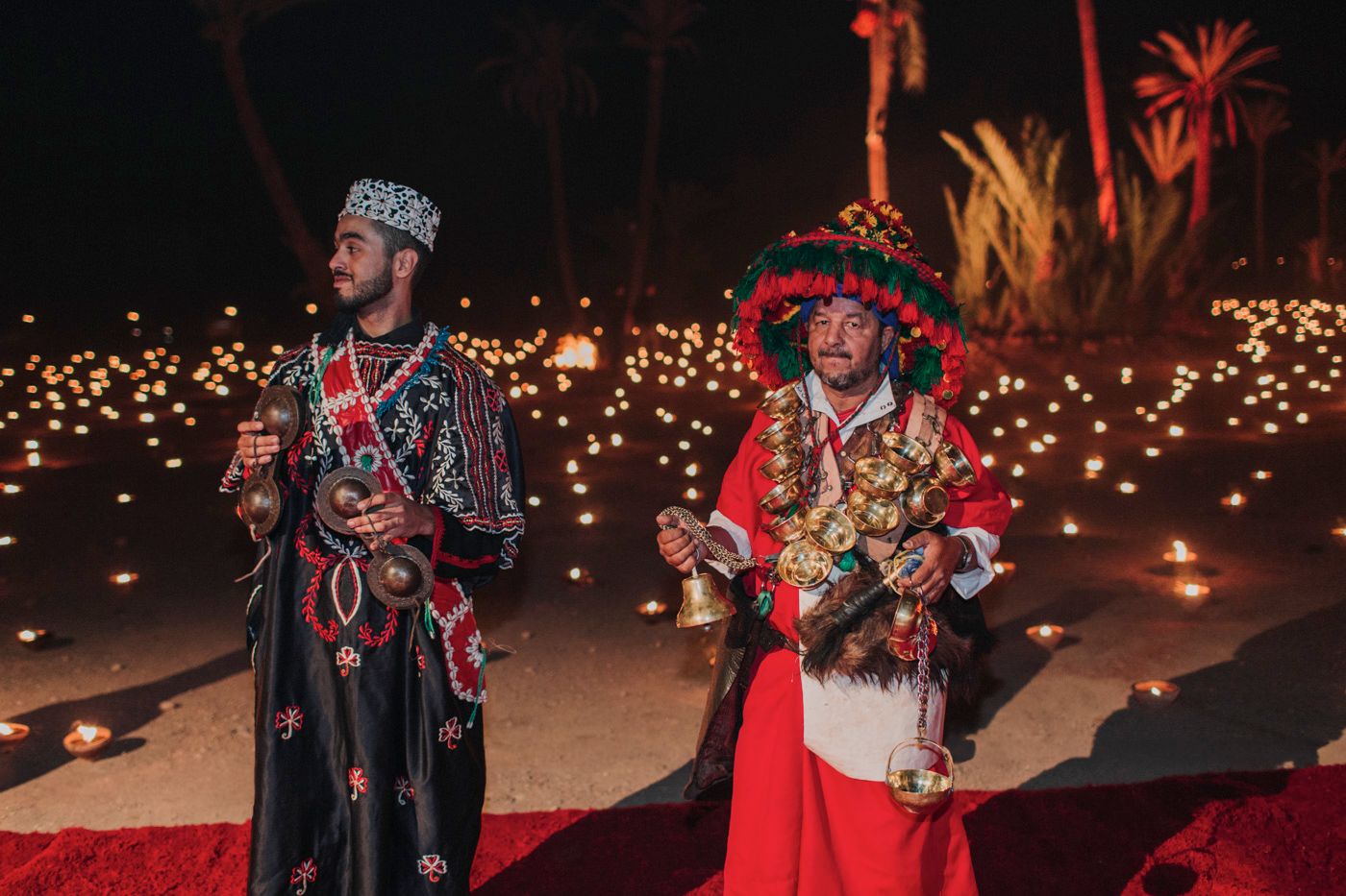 Traditional performers in ornate costumes entertain guests during a festive nighttime celebration.