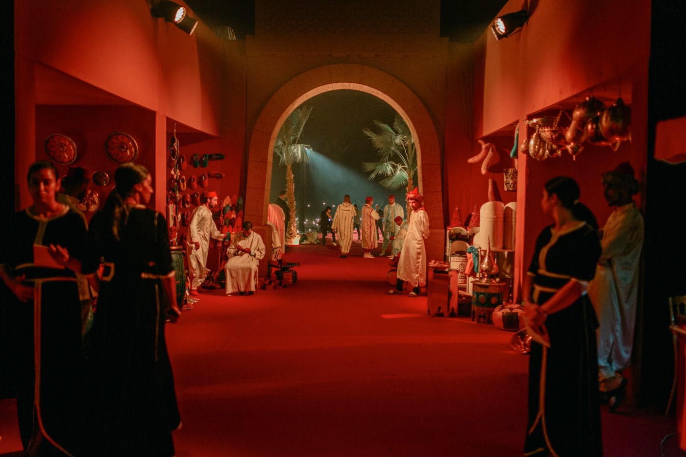 Red-lit archway corridor filled with performers and guests at a Moroccan-themed event.