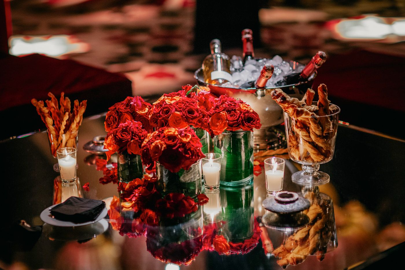 Elegant table centerpiece with red flowers, candles and refreshments.