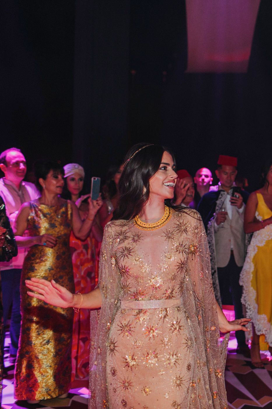 Party guest in a shimmering beige dress enjoying the festive atmosphere under purple lighting.