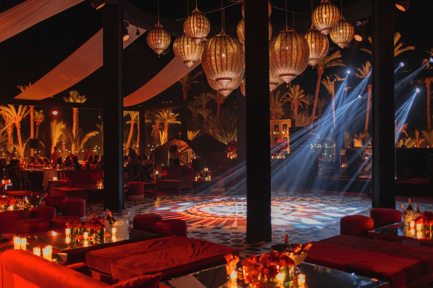 Oriental lanterns hang from ceiling beams while blue spotlights create dramatic atmosphere.