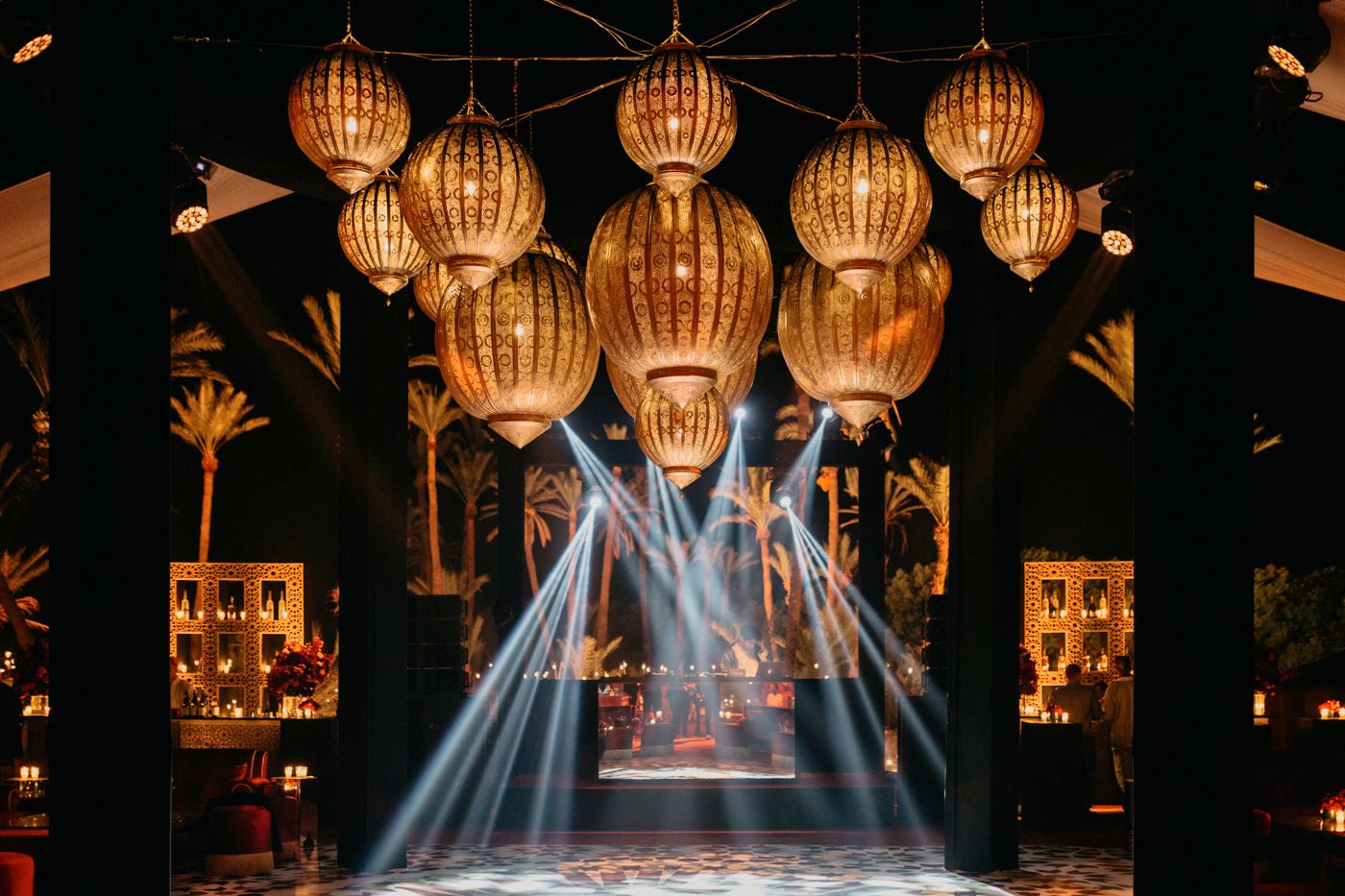 Glowing paper lanterns suspended above dance floor with dramatic blue light beams.