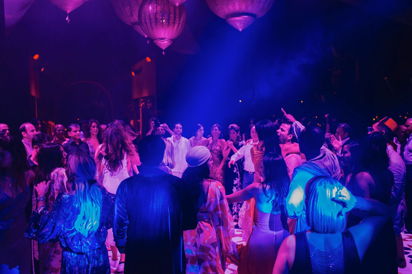 Dance party scene with blue and purple lighting illuminating a crowded dance floor.