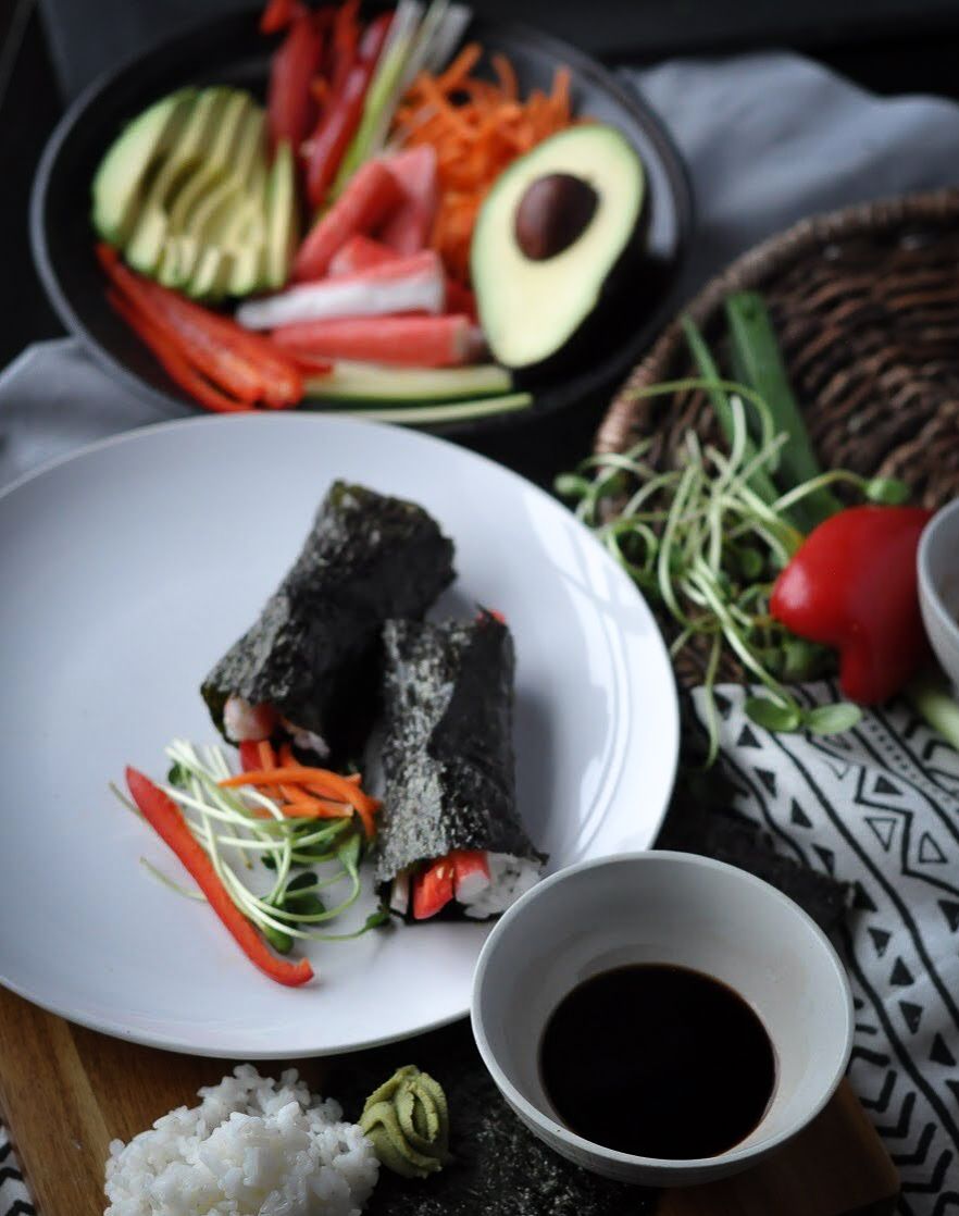 Sushi handroll platter with fresh vegetables, avocado and soy sauce dipping bowl.