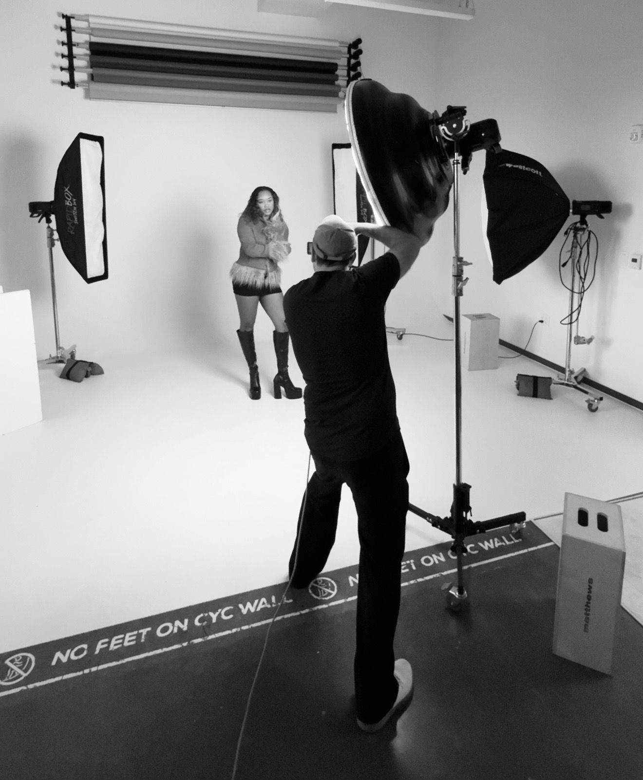 Behind-the-scenes photo of photographer shooting model in professional studio setup.