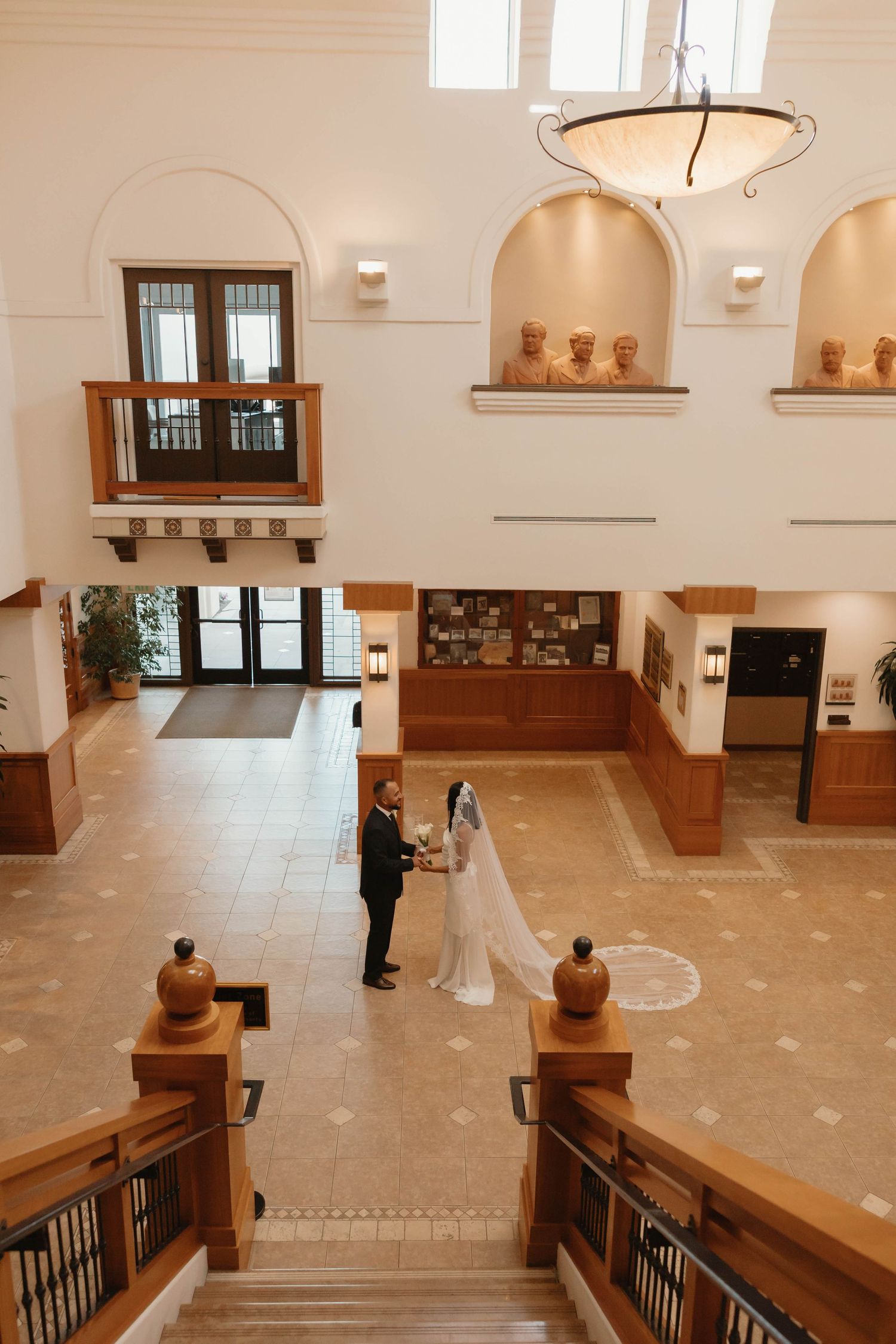 Interior view of a modern museum gallery space with wooden railings and beige marble floors showing multiple display areas.