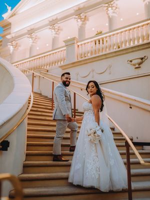 A romantic first look moment unfolds on an elegant white staircase during a wedding celebration.