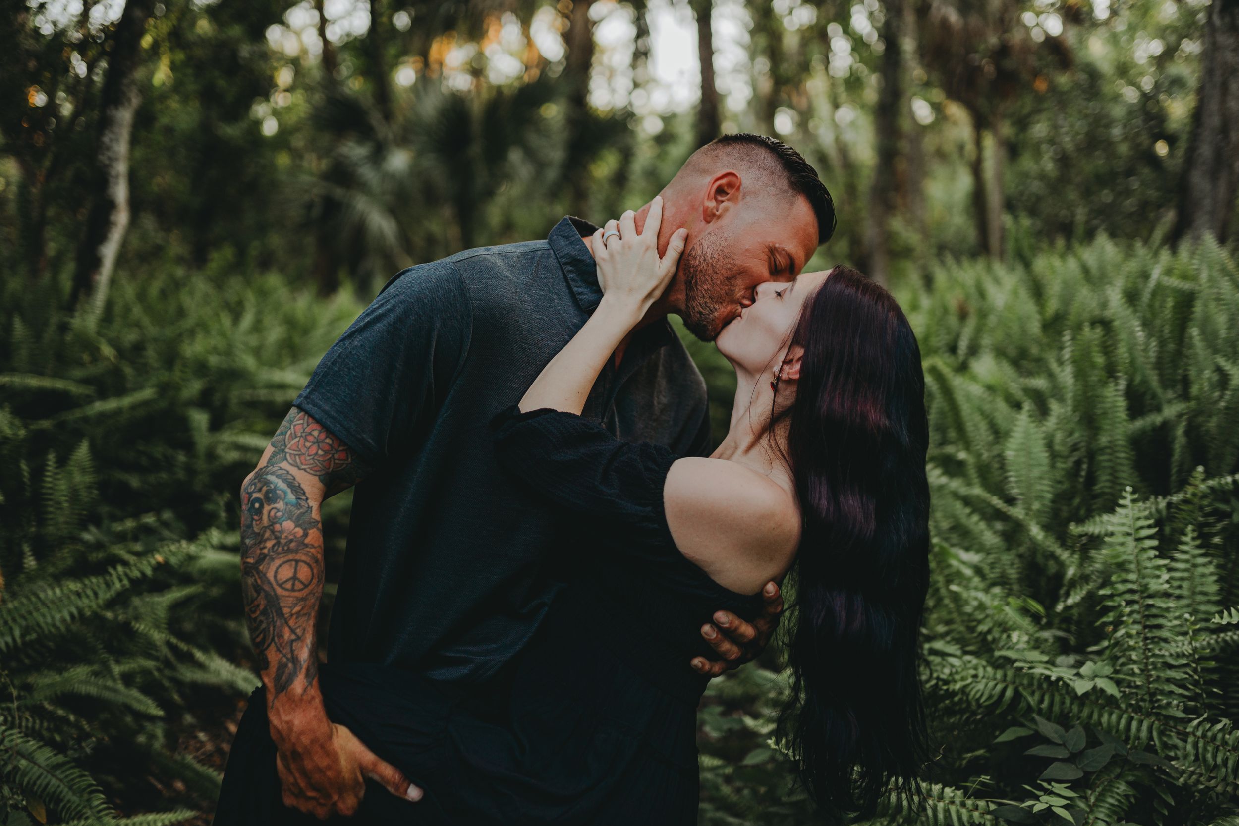 An intimate moment captured between two people in a lush green forest setting.
