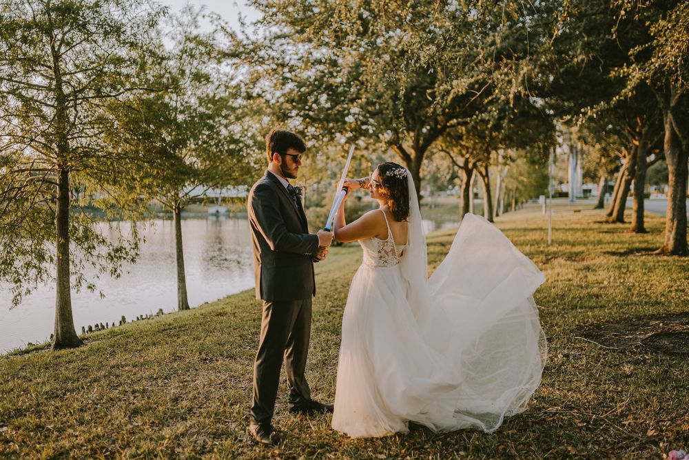 Golden sunlight streams through trees during outdoor wedding photography session in natural setting.