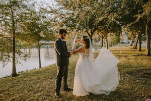 Golden sunlight streams through trees during outdoor wedding photography session in natural setting.