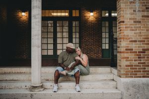 A couple shares intimate moment on brick building steps at dusk.