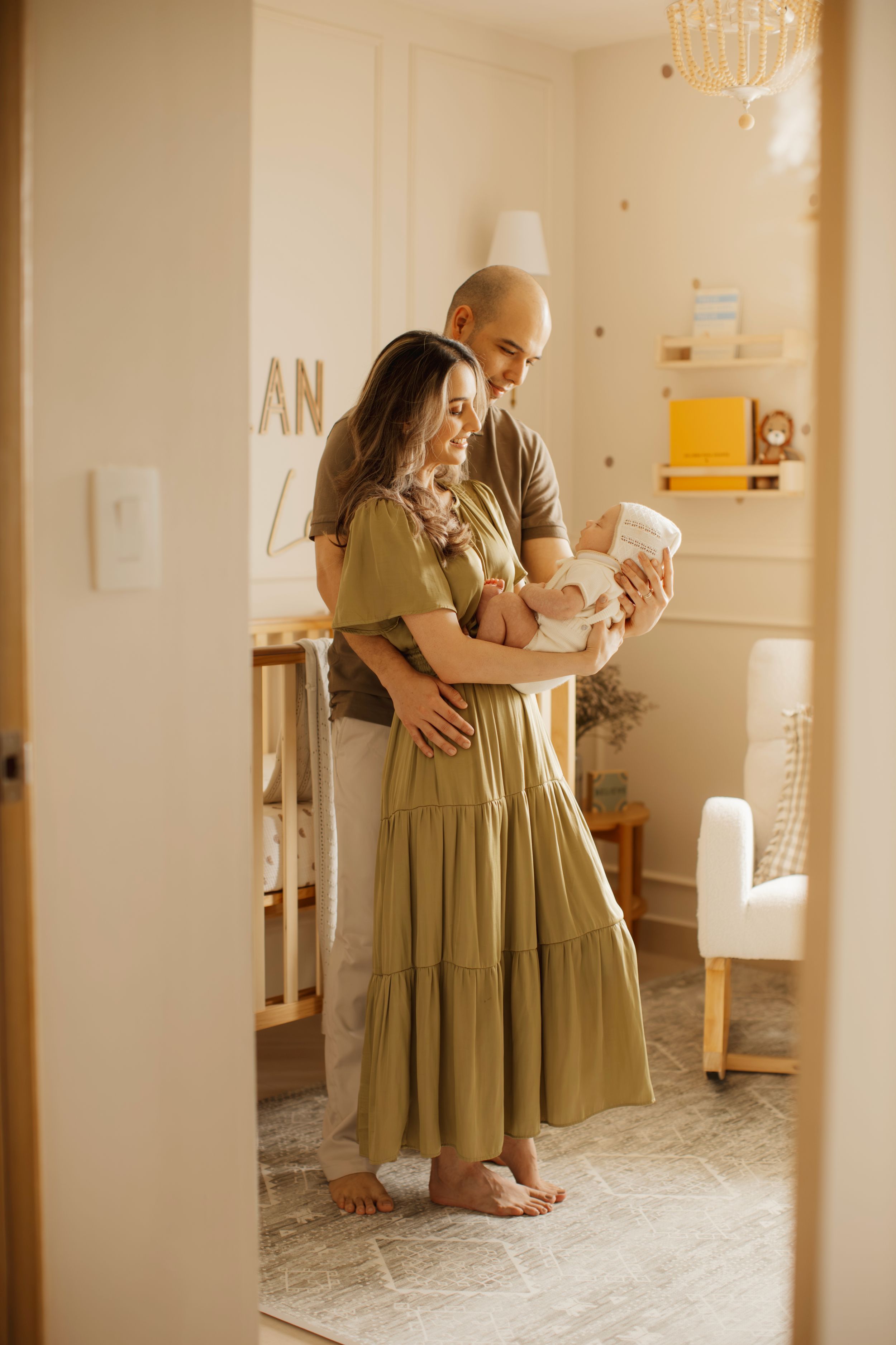 Tender family moment with parents holding newborn baby in nursery.
