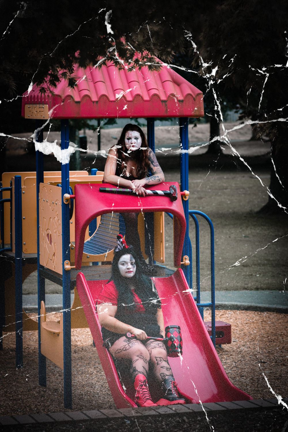 A child in dark clothing plays on pink playground equipment under a cloudy sky.
