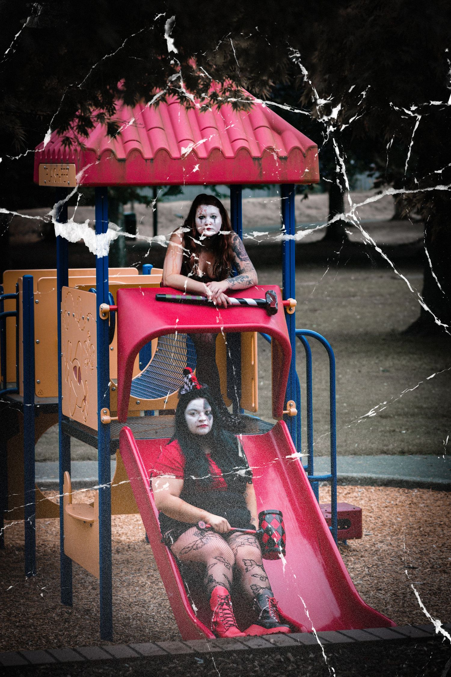 A child in dark clothing plays on pink playground equipment under a cloudy sky.