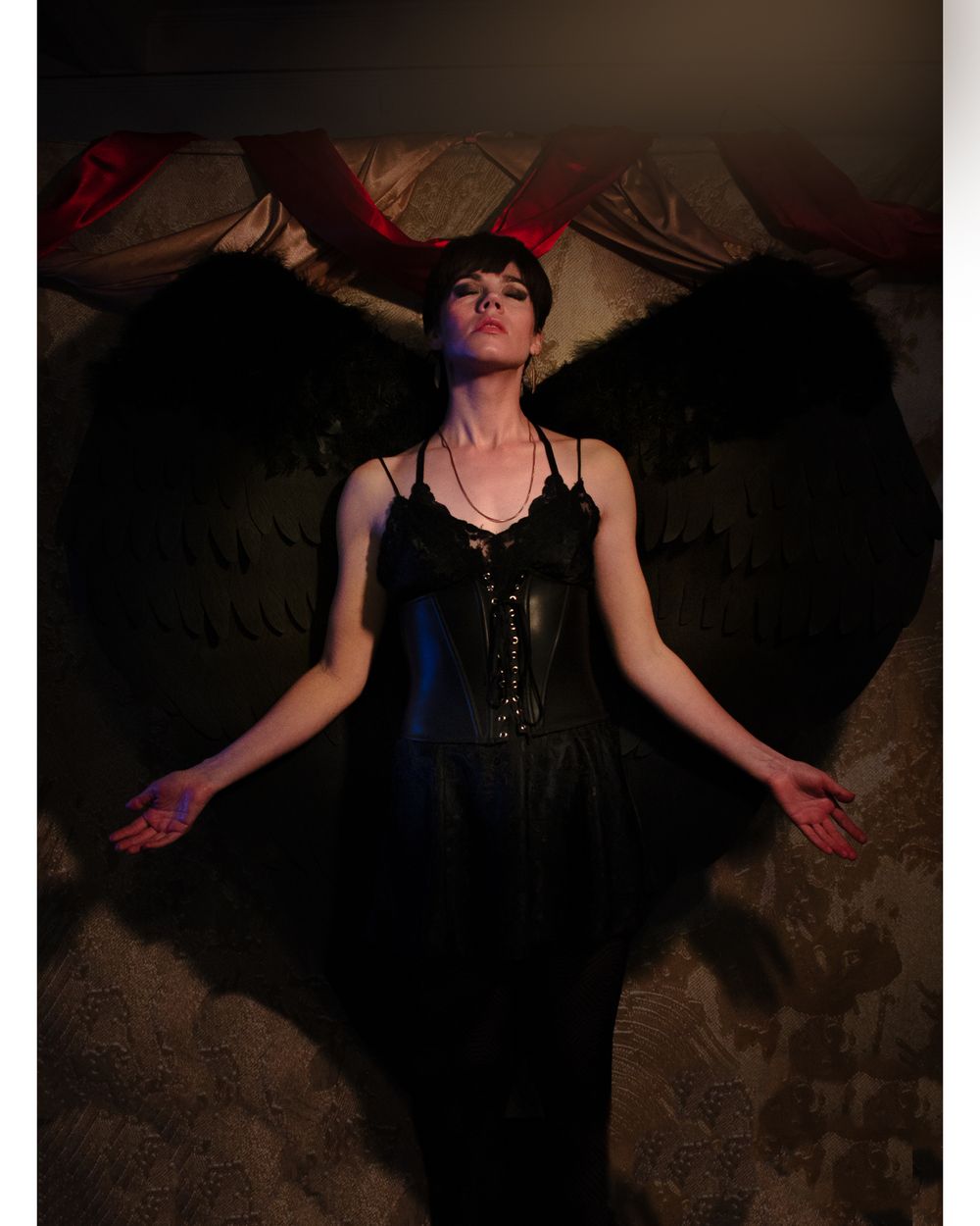 Dramatic portrait with black wings in dark moody lighting.