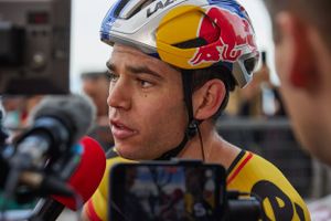 A cyclist wearing a Red Bull helmet speaks to media during an interview.