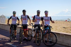 Four cyclists pose with their bikes along a coastal pathway.