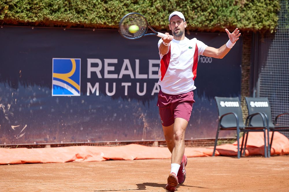 Tennis player hitting forehand shot in front of Reale Mutua sponsorship wall.