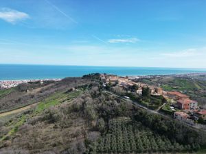 Aerial view of coastal Italian village perched on hillside overlooking Mediterranean Sea.