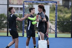 Players celebrate during a match on blue padel court.