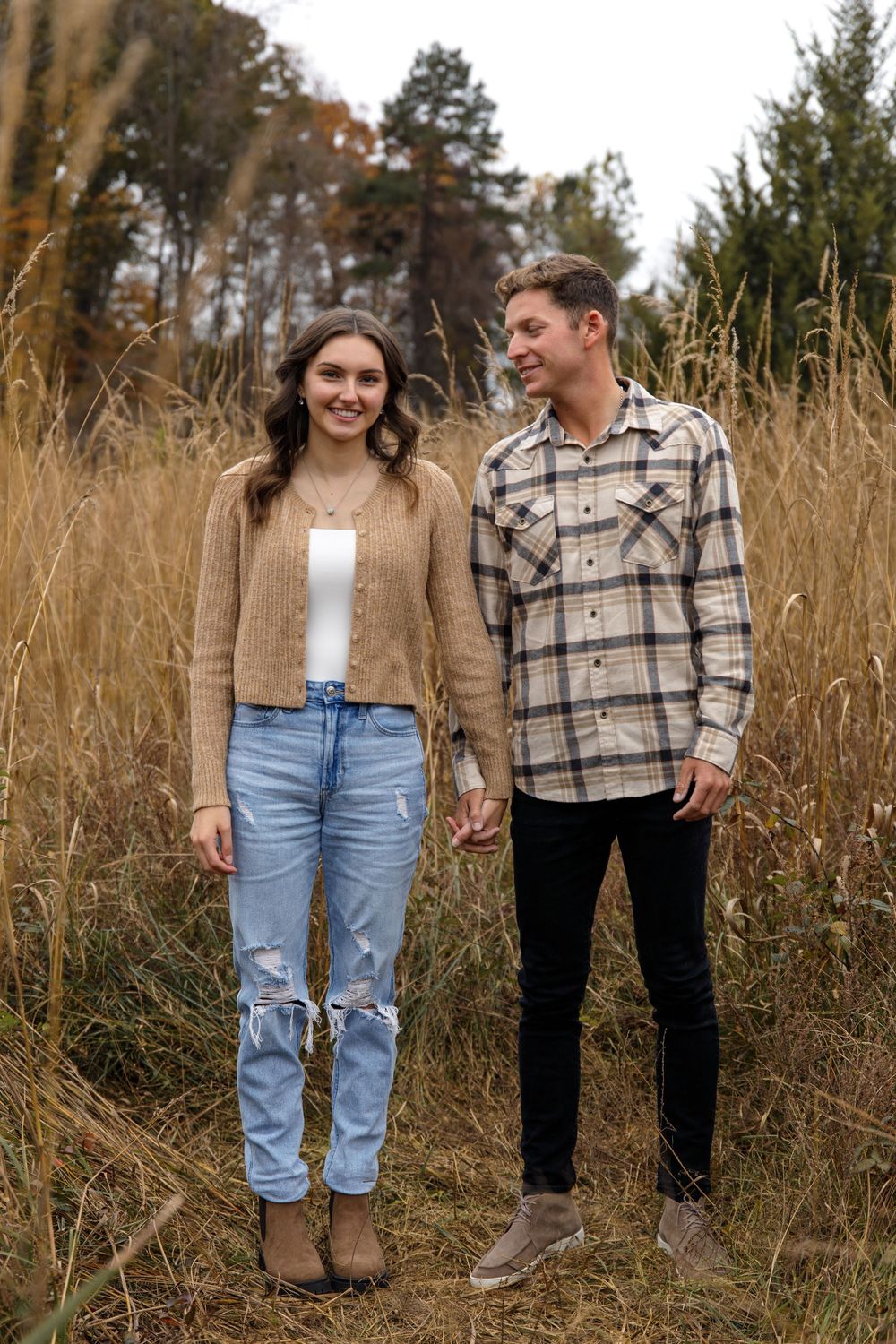 Candid moment of couple laughing together in autumn field setting.