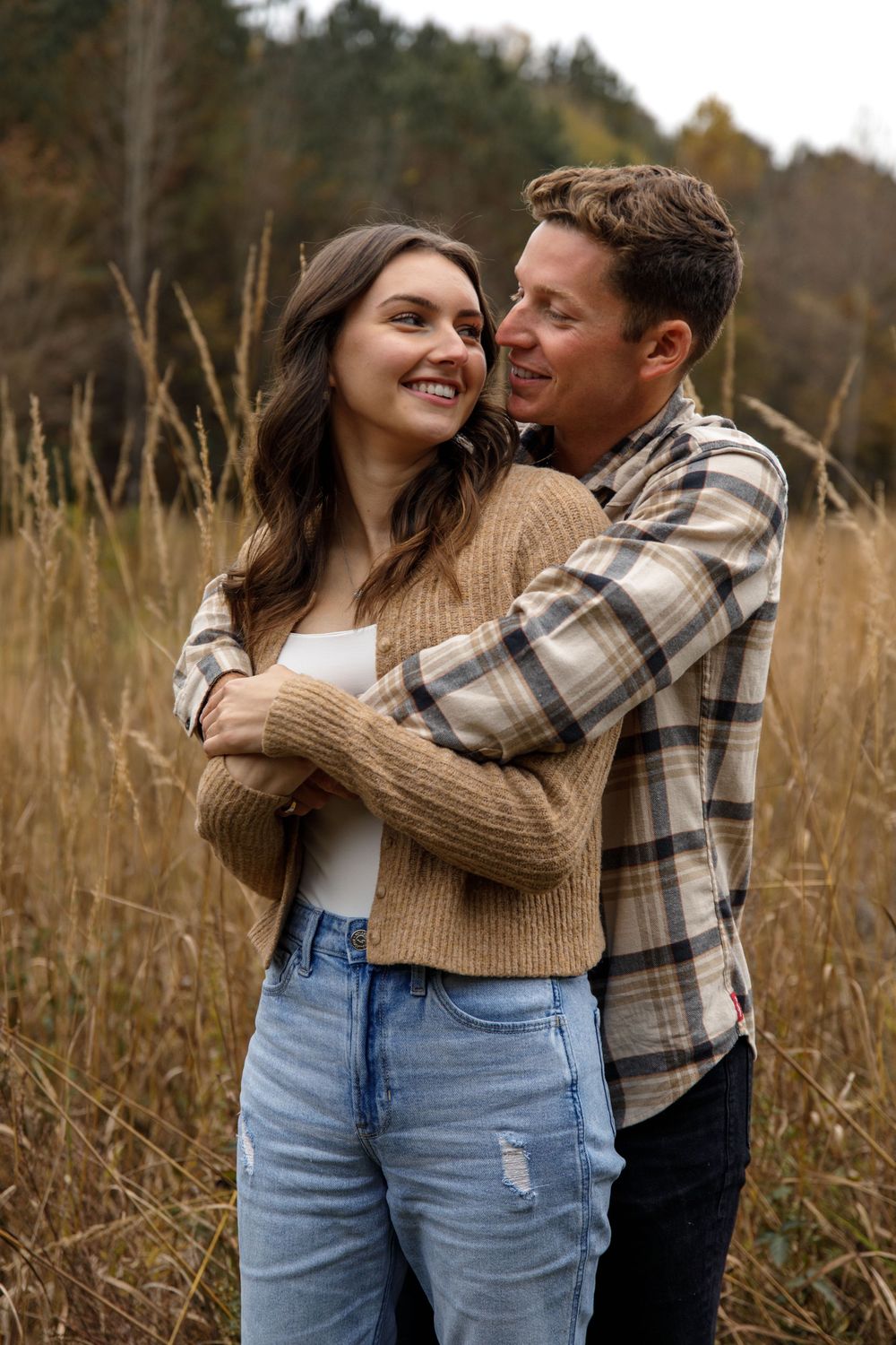 Couple in casual fall attire sharing intimate moment in rustic outdoor setting.