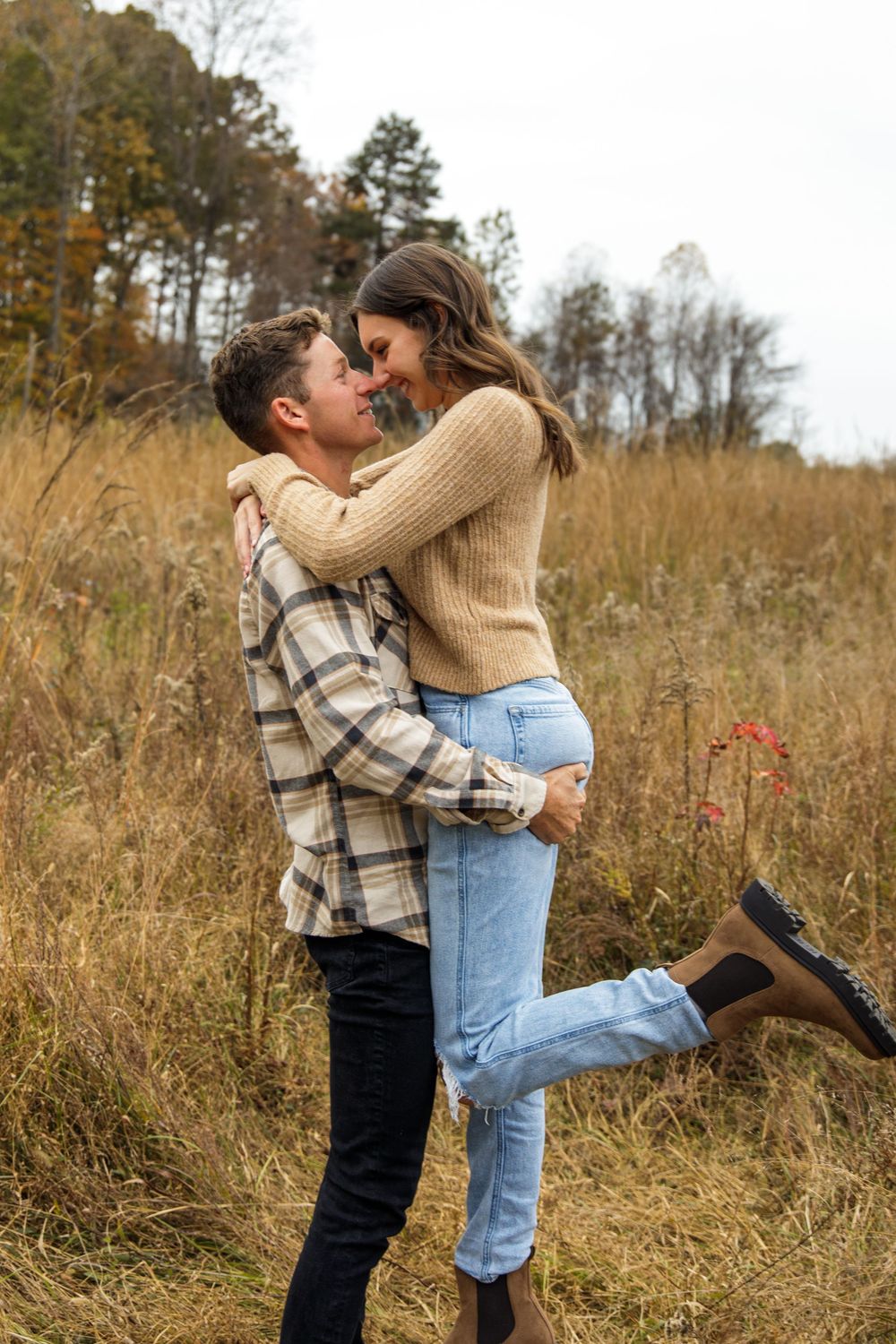 Playful embrace captured in golden meadow during autumn photoshoot.
