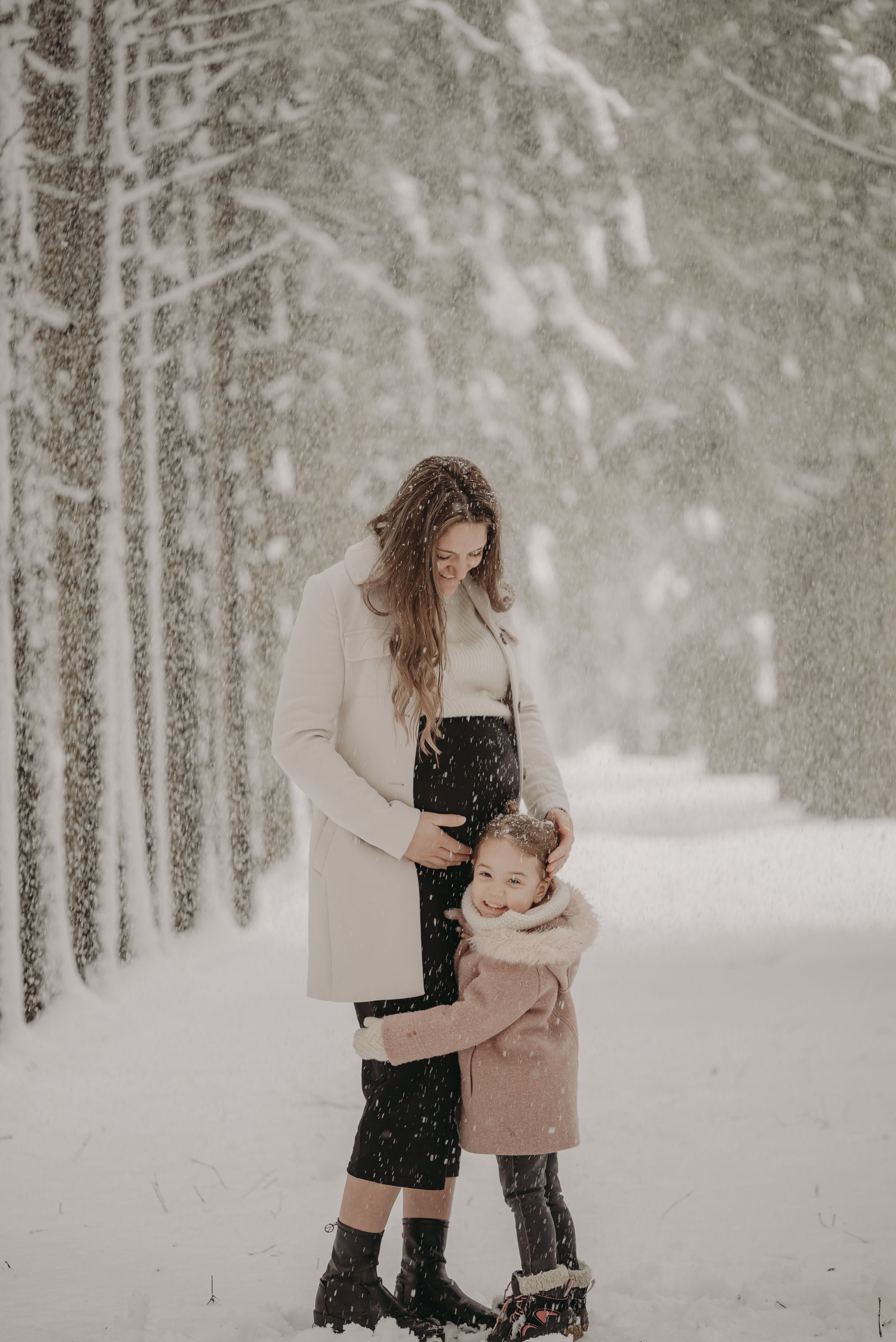 A tender winter moment between two people embracing in a snowy forest path.