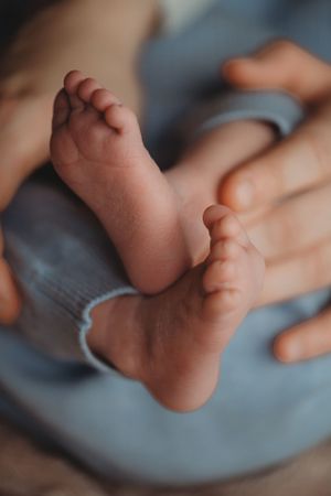 Close-up of tiny newborn feet against a soft blue fabric background.
