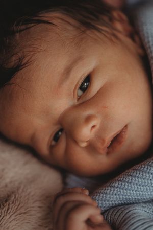 Close up view of a baby's face resting on soft fabric with gentle lighting and peaceful expression.