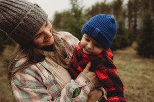 Parent and child sharing a tender moment while wearing winter hats and plaid clothing.