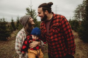 Family sharing loving moment together at Christmas tree farm in winter clothing.