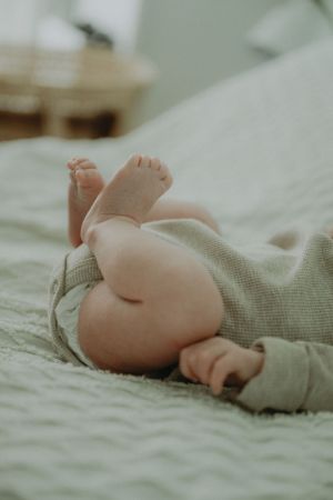 Close-up of tiny baby feet and legs against soft textured bedding.