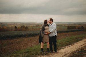 Couple sharing intimate moment against scenic rural landscape at dusk.