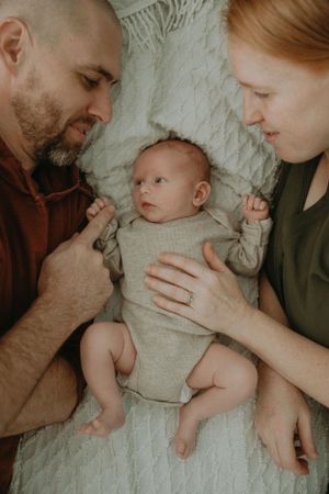 Intimate family moment with newborn baby on white blanket.