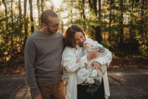 A tender family moment captured in golden autumn sunlight on a forest path.