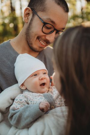 A delightful candid moment of a baby laughing while being held outdoors in autumn.