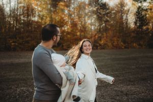 A playful family moment captured in motion during golden hour in an autumn field.
