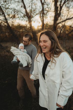 Family enjoying a candid outdoor moment with newborn baby during sunset in autumn.