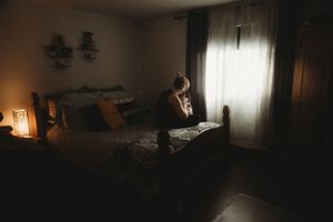 A dimly lit bedroom scene with soft window light creating a moody atmosphere.
