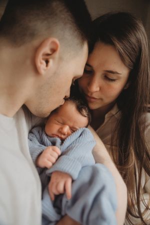 Intimate family moment with newborn baby in blue sweater.