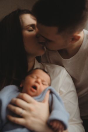 An intimate family moment with a newborn baby wrapped in a light blue blanket.