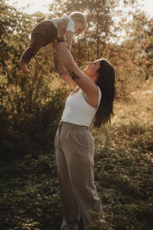 Parent lifting child high into air against golden sunset in nature setting.