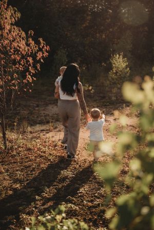 A sunset walk along a nature path shows a pair walking hand in hand through autumn foliage.