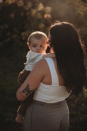 A candid outdoor portrait showing distinctive tattoo artwork against golden sunset lighting.