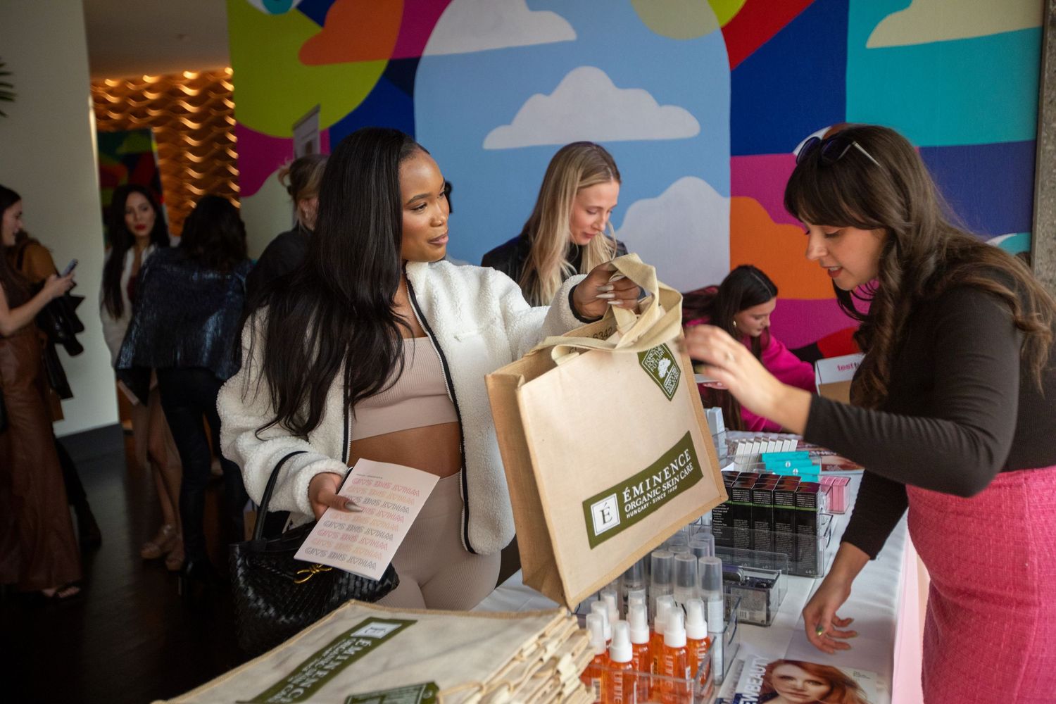Product sampling at a retail event with branded shopping bags.